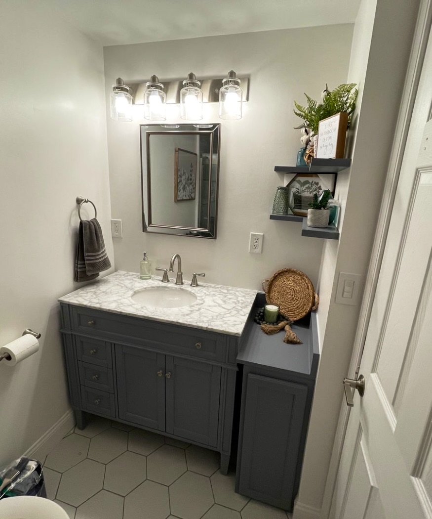 Bathroom with a gray vanity, marble-look top, framed mirror and four-light fixture